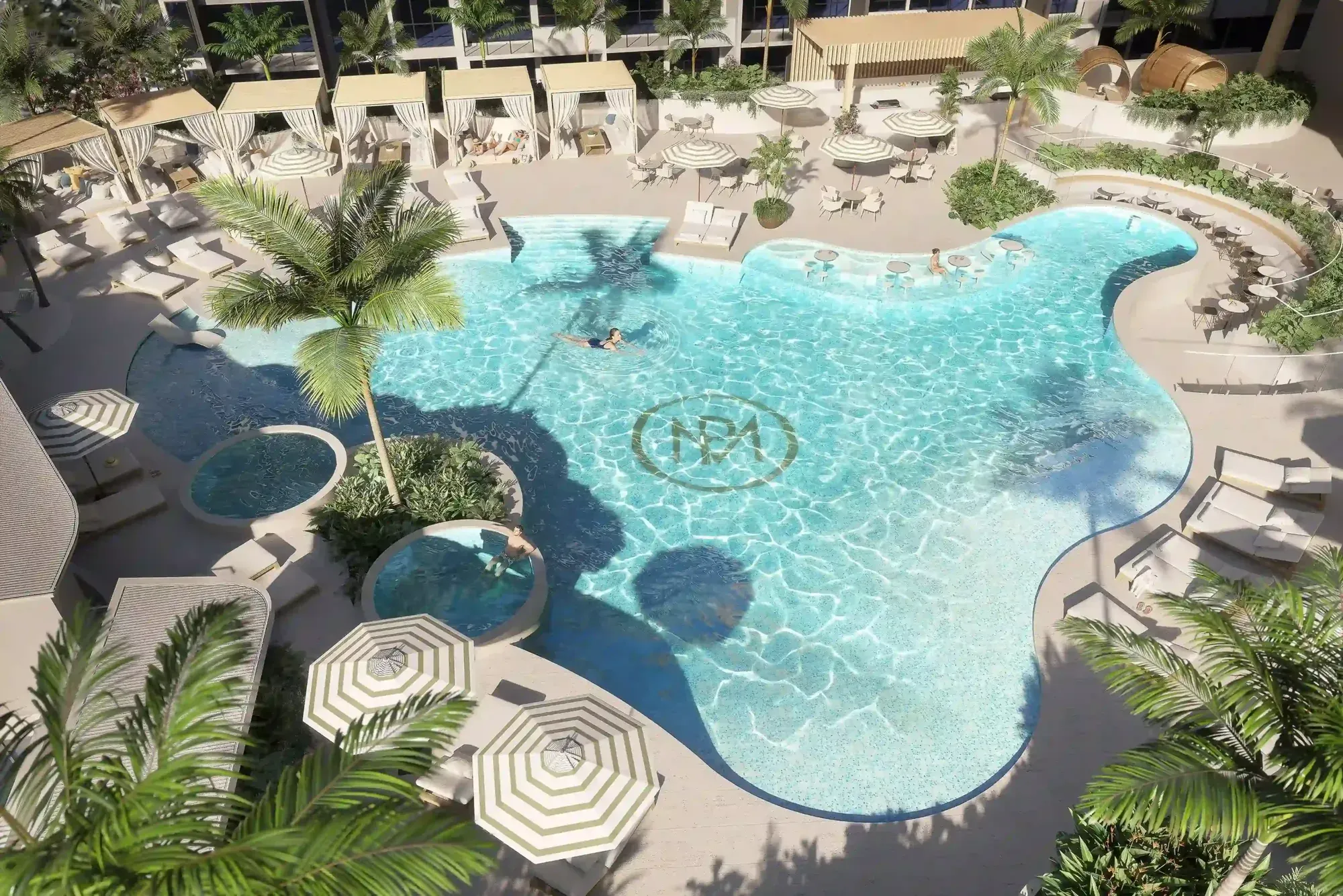 Render of the Monarch Place resort pool from above: a freeform lagoon pool ringed by cabanas, umbrellas and palms